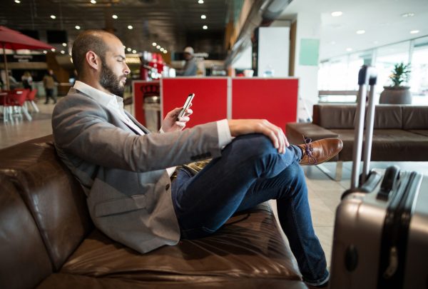 Businessman using mobile phone in waiting area at airport terminal